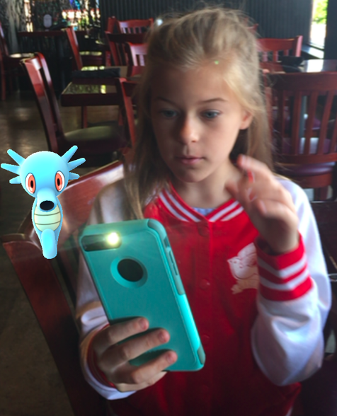 Young Gen Z girl with iPhone playing Pokemon Go